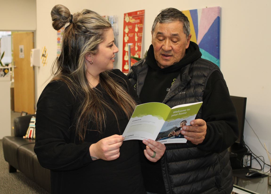 Two people reading a LinkPeople booklet at the Rotorua LinkPeople Office,